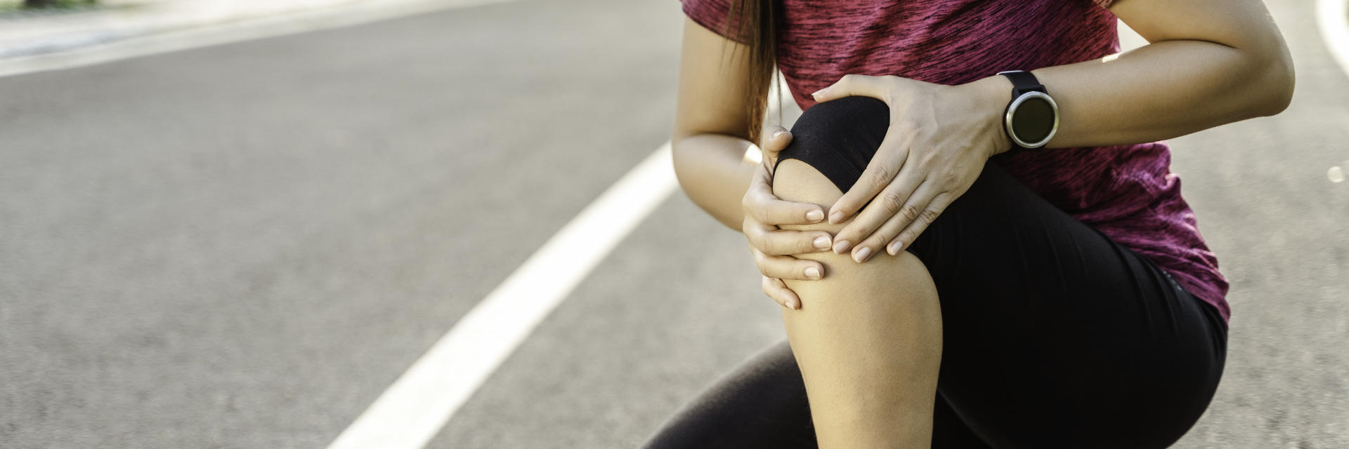 An athlete girl holding her painful knee with both hands.