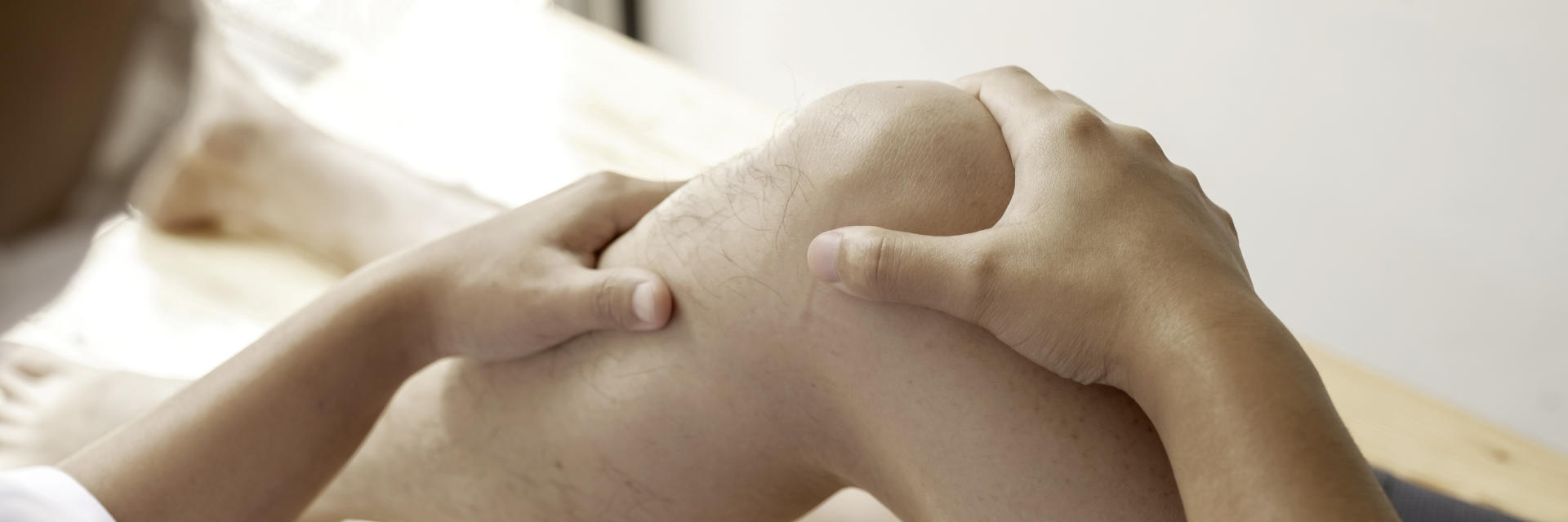 An orthopedic surgeon examining patient's knee.