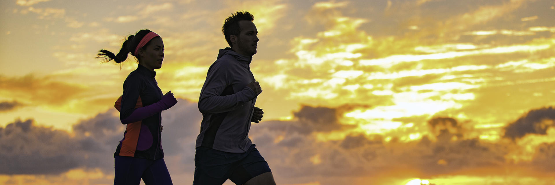 A couple running outdoors by the sunset.