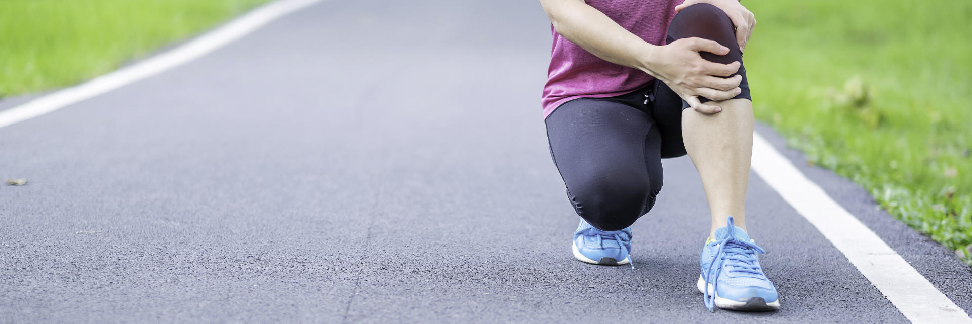 A kneeling athlete woman holding her knee in pain.