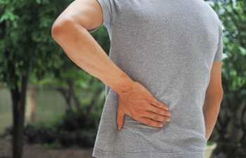 man holding her lower back while and suffer from unbearable pain