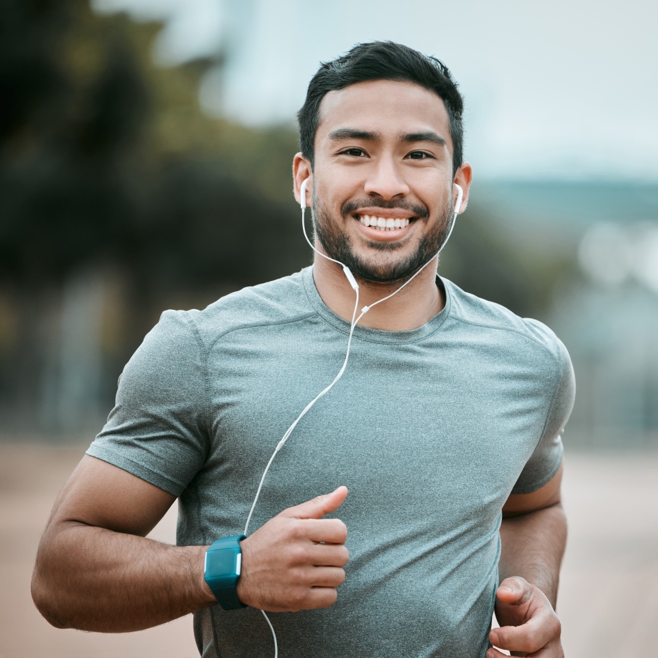 Fitness, portrait and man running with earphones for music, radio or sport podcast for motivation. Sports, exercise and male athlete runner doing outdoor cardio workout for race or marathon training