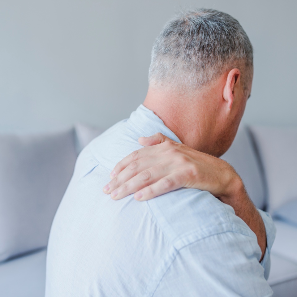 Young man suffering from pain in shoulder, closeup.People, healthcare and problem concept - unhappy man suffering from neck or shoulder pain at home. Shoulder pain Caused by not taking care of health.