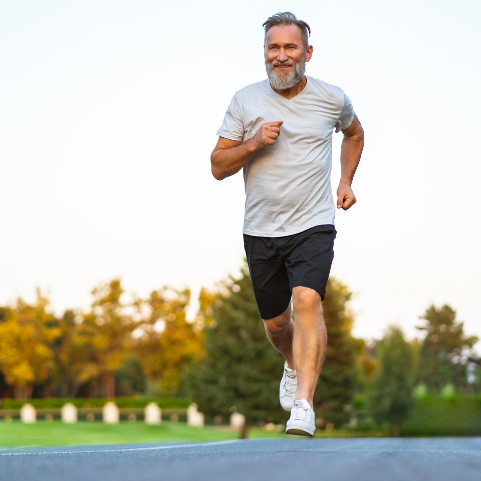 The smiling happy elderly man running on the road