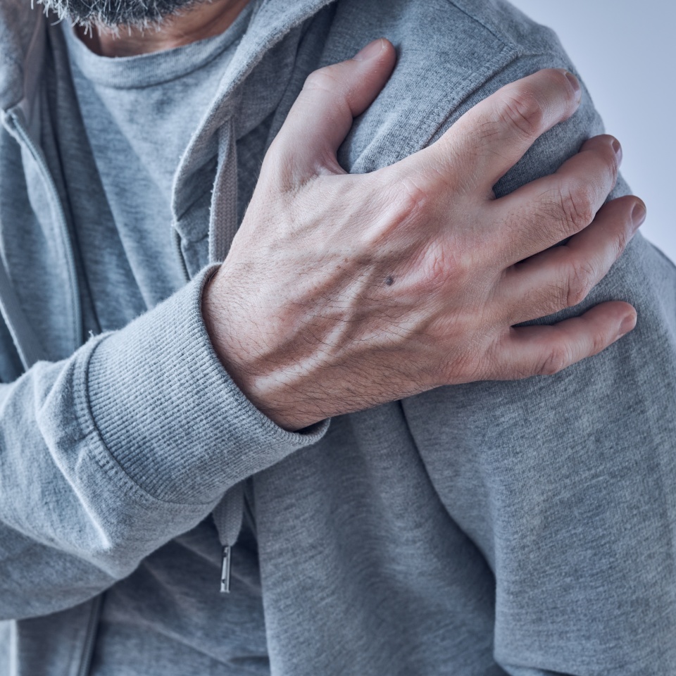 Shoulder joint pain, man with severe ache as symptom of osteoarthritis, close up with selective focus