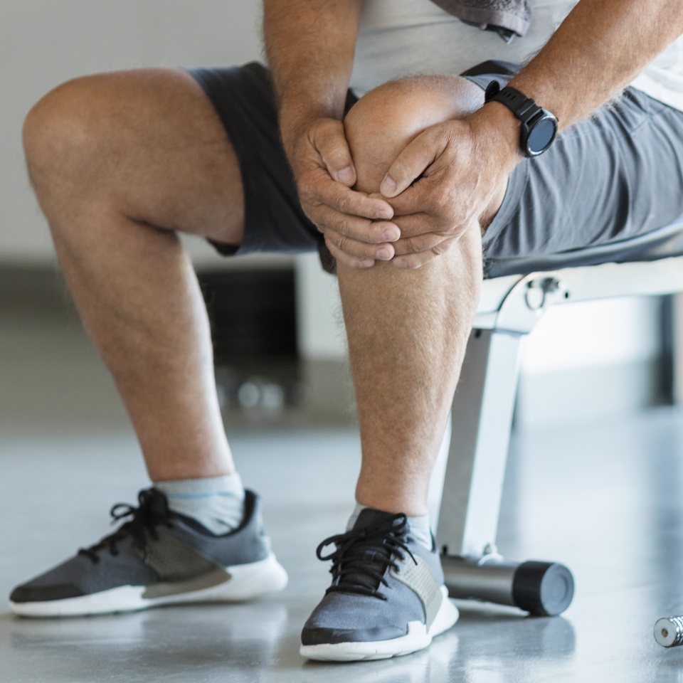 Active senior man in gym with knee injury