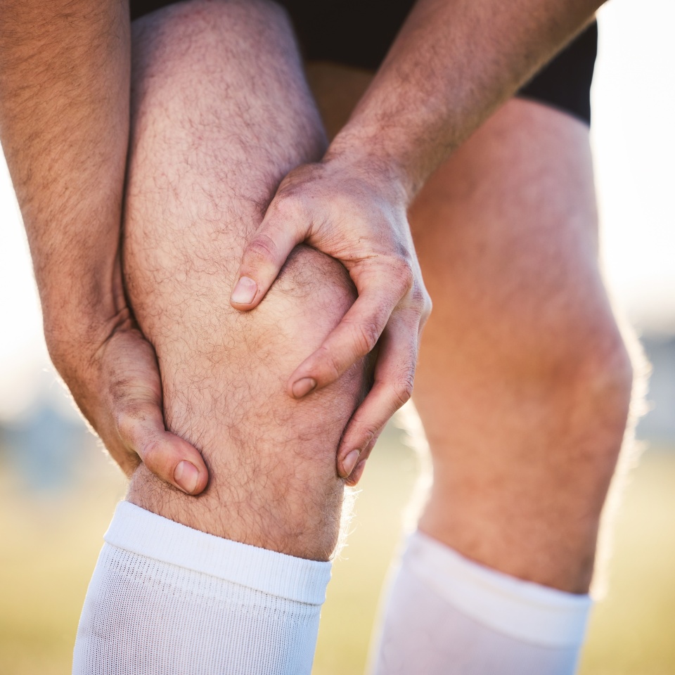 Knee pain, man with injury and fitness accident, athlete outdoor with cramps and muscle tension. Exercise, sports and male person with hands on leg, health crisis and rugby player with inflammation