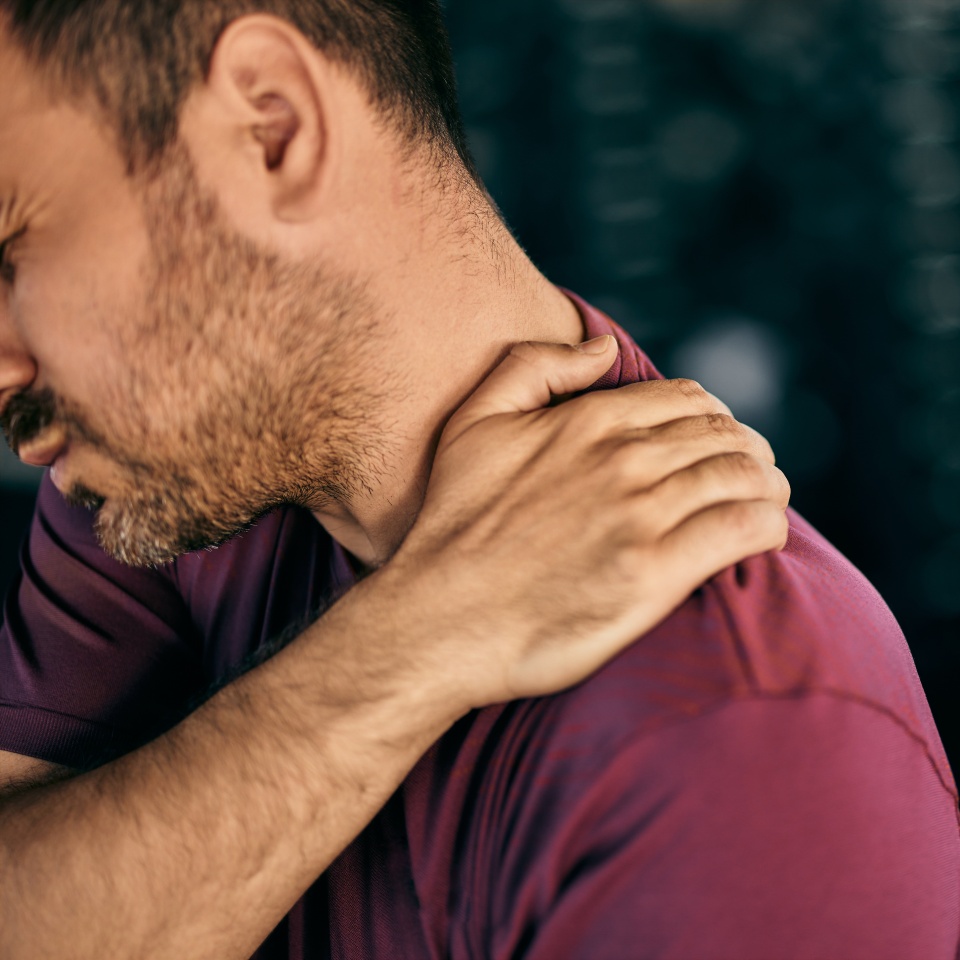 An injured male having a lot of pain, sitting at the gym, holding his back.