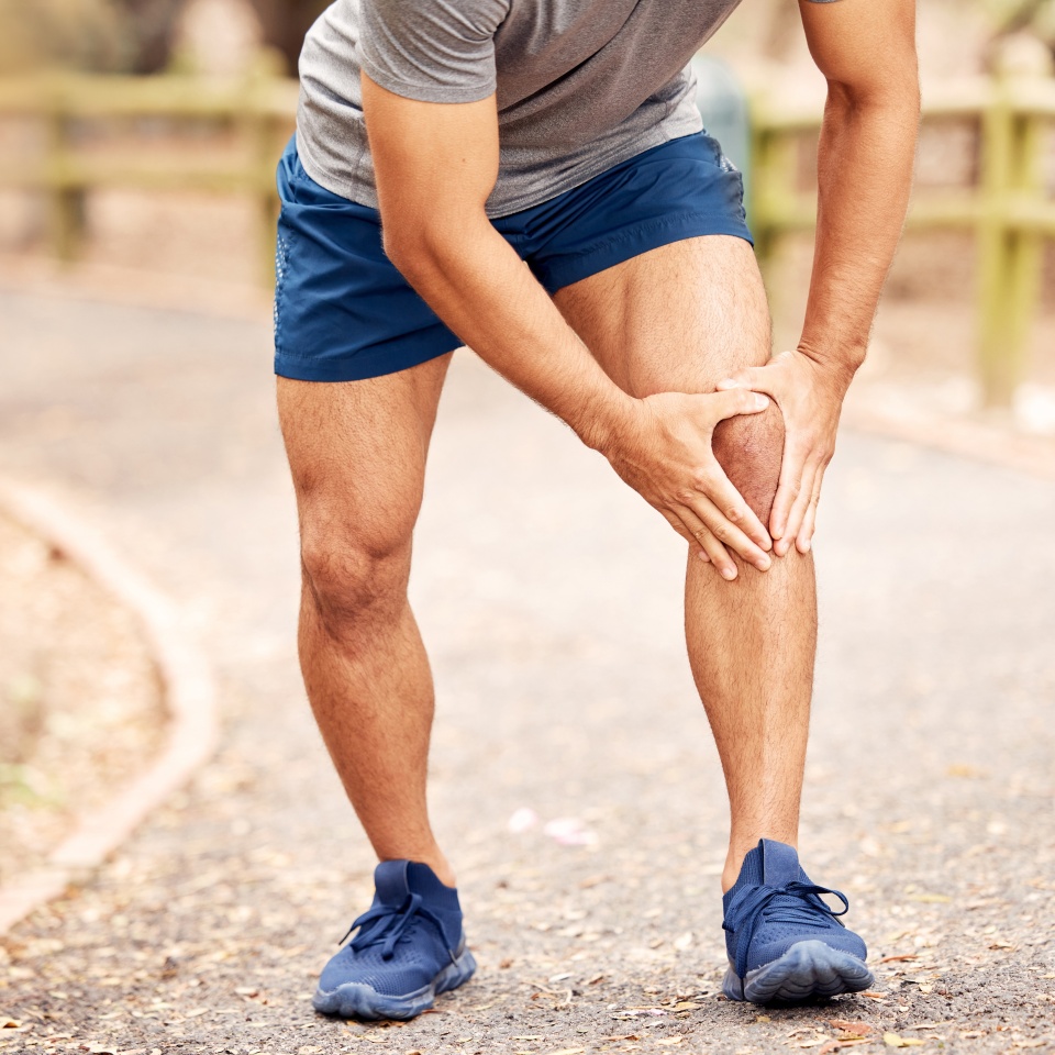 Outdoor, knee pain and hands of person after fitness accident, injury and muscle tension. Nature, road and male runner with fibromyalgia, leg inflammation and massage joint during training session