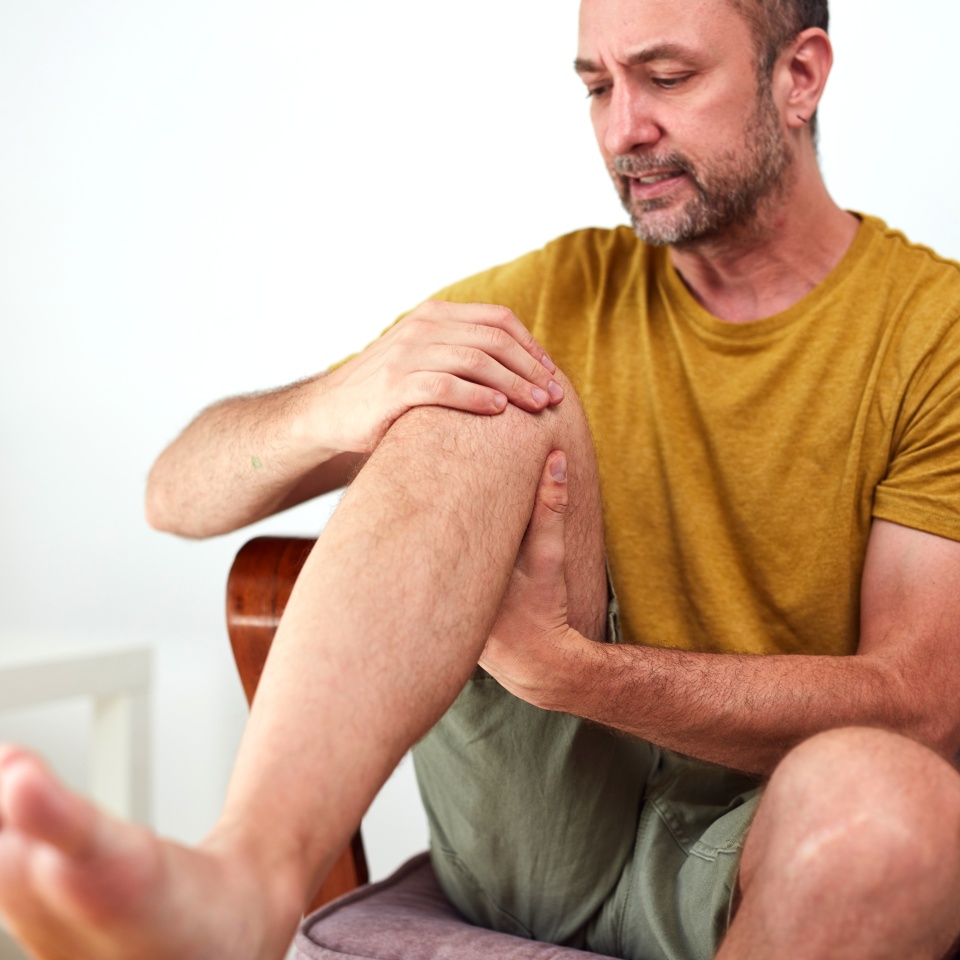 Man with painful knee and leg injury at home.