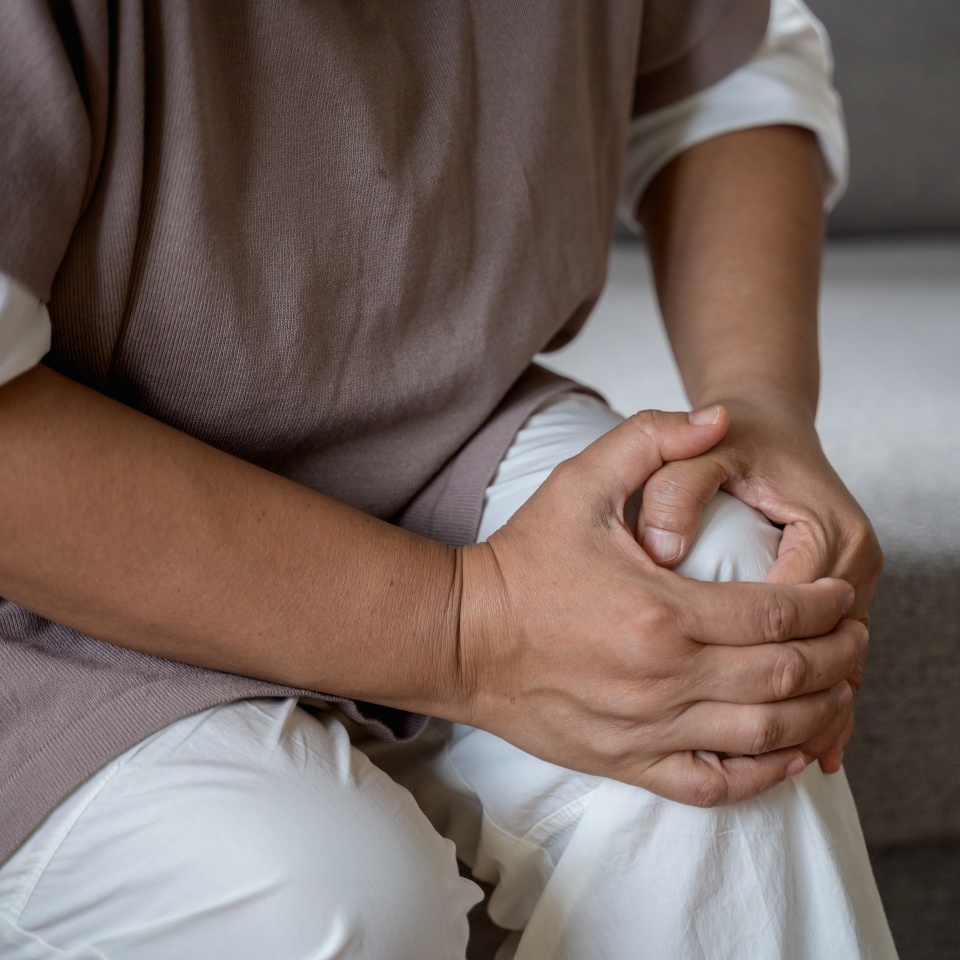 Mature Asian female suffering from knee pain osteoarthritis. Close up senior woman holding her knee due to physical injury while sitting alone at home. rheumatoid arthritis disease in Adult.