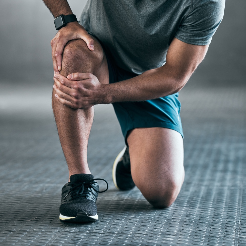 Man, hands and knee pain with injury in muscle tension, accident or fitness on floor at gym. Closeup of male person with sore leg, ache or inflammation in strain, pressure or sprain at health club