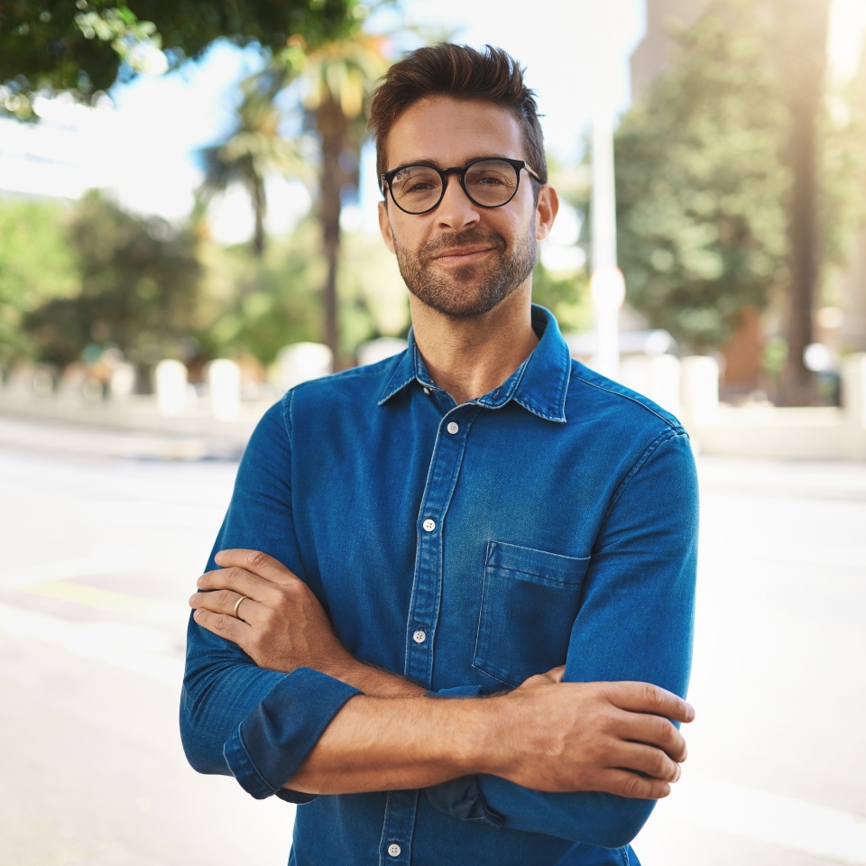 City, pride and man in portrait for travel, vacation holiday and adventure with smile in summer. Happy, male person and traveler with flare for weekend journey, glasses and arms crossed in California