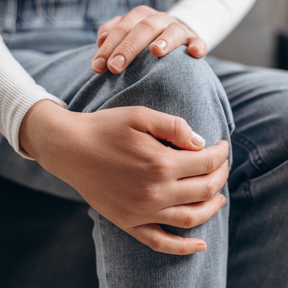 Arthritis chronic disease problem concept. Close up of young caucasian female touching her leg feeling pain in knee joint, and can't walk properly because of inflammation and pain