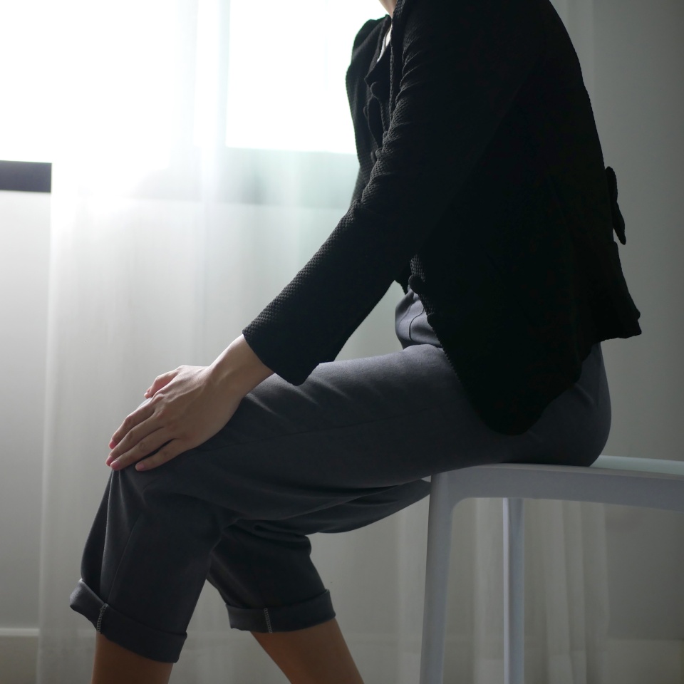 Business woman sits on a chair for a long time cause knee pain The girl's hands wrapped around her knees. Hold and massage knees. Health care concept.