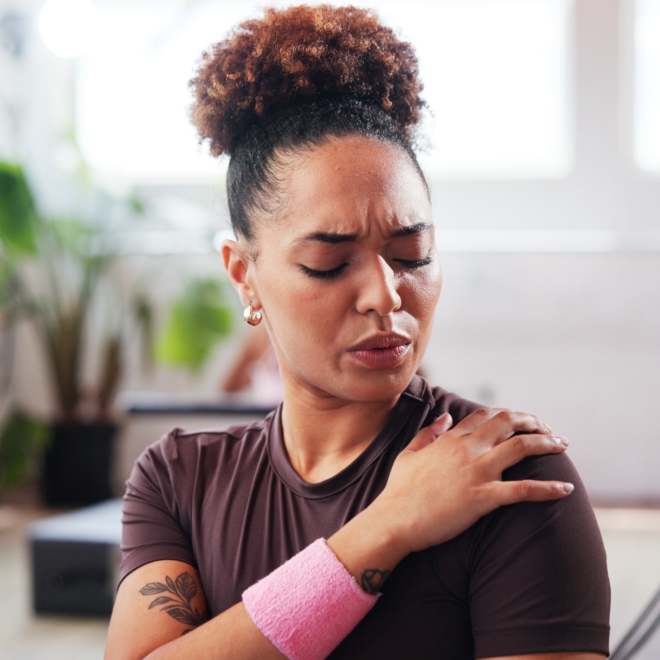 Gym, fitness and woman with shoulder pain for injury, muscle tension and inflammation in studio. Breathing, female person and wellness with hand massage for joint ache, discomfort or sore for workout