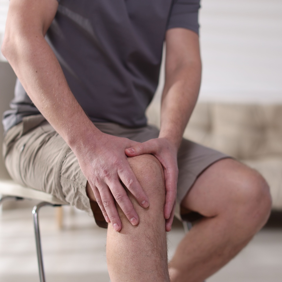 Man suffering from knee pain at home, closeup