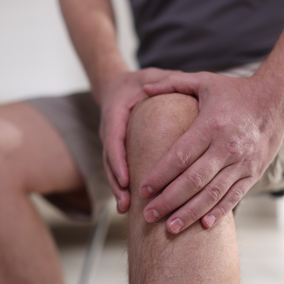Man suffering from knee pain at home, closeup