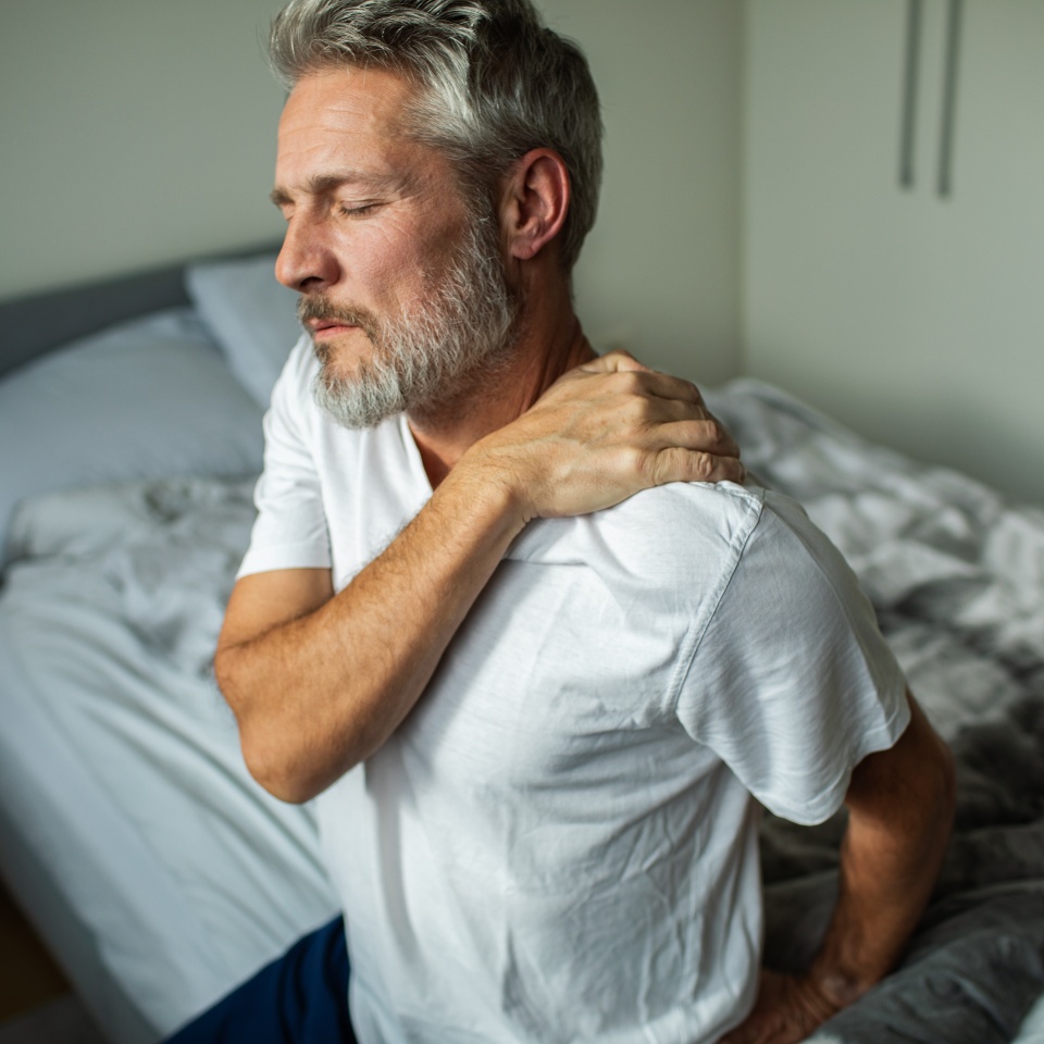Middle-aged man with shoulder pain in bedroom